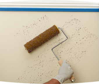 Person speckling the wall with a paint roller