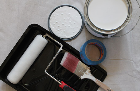 Behr Paint roller, paint brush, painter’s tape, and a gallon of Behr paint