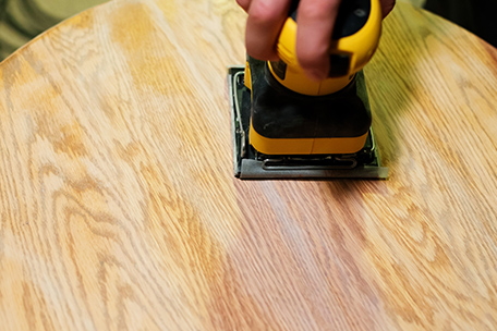 Sanding the table top with a palm sander