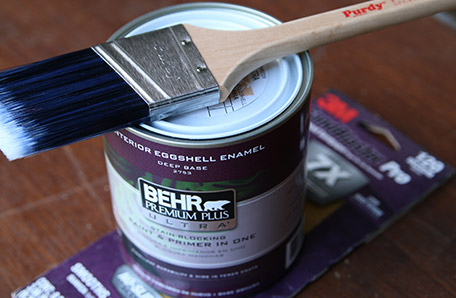 A clean paintbrush, a quart of Behr paint and a sleeve of sandpaper