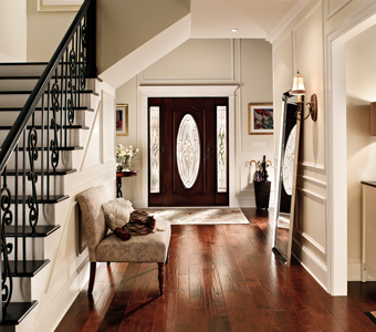 Large entrance with off-white walls, dark wood floors, black stair railings, and black door.
