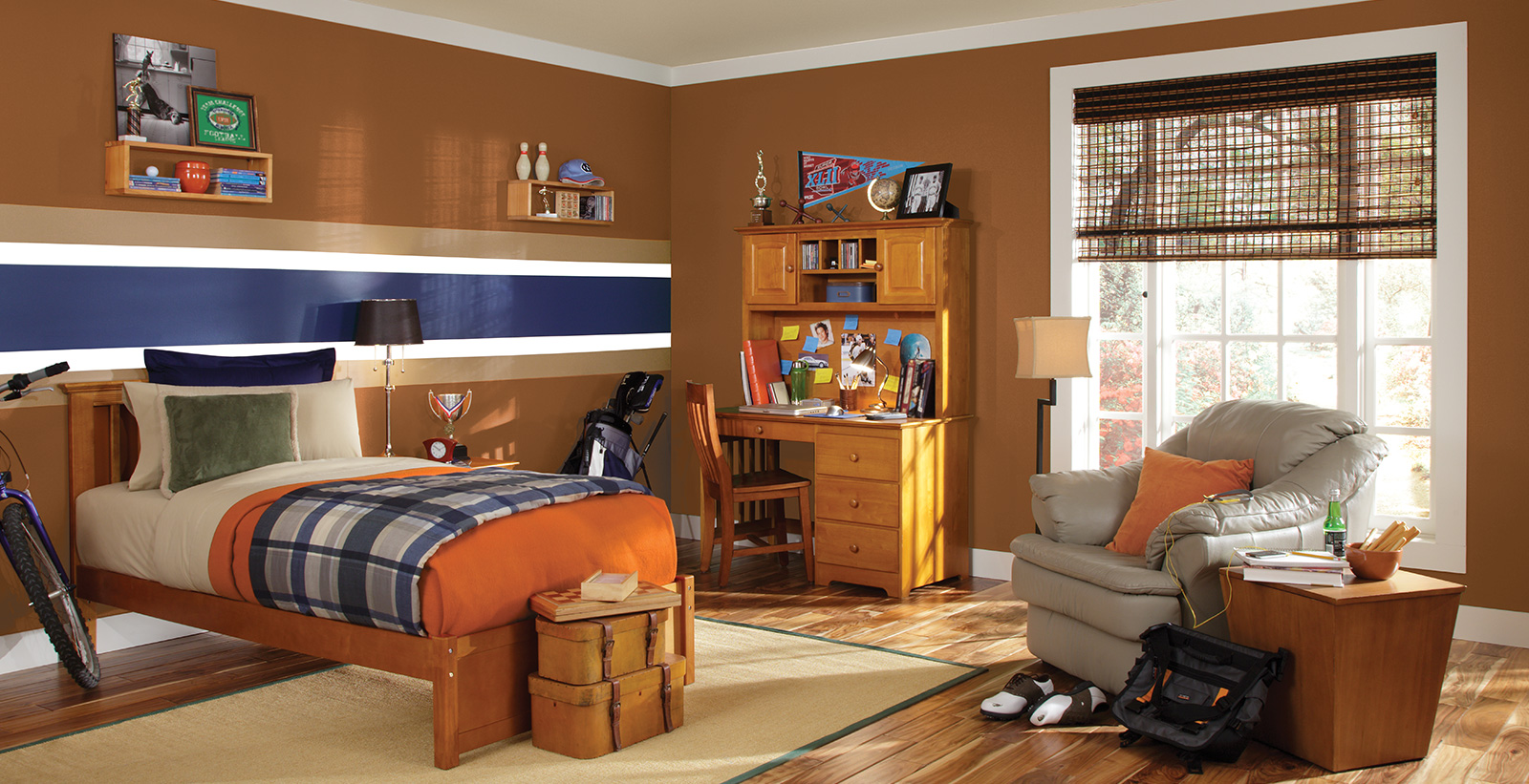 Sporty styled youth room with orange, blue, white, and brown horizontal striped walls, white on the trim, wooden desk with sports memorabilia, and a wooden bed.