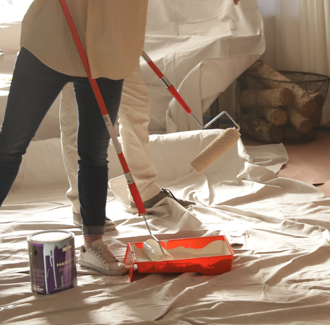 Smaller Image of person painting with drop clothes and paint roller for mobile