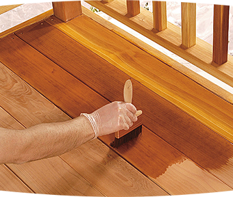 Person staining wood deck with paint brush