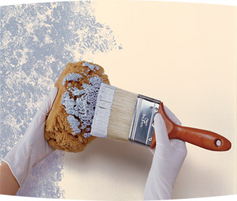 Person applying paint to a sponge and then sponging the wall