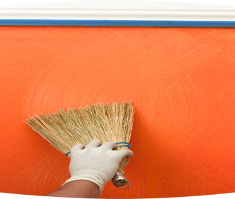 Person applying wavy lines of paint onto wall with a broom