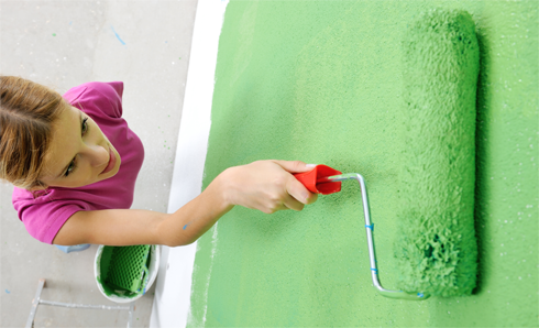 Woman in pink shirt rolling green paint on the wall