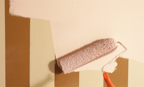 Paint roller painting tan color on a wall