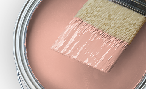 Paint brush being dipped in a can of light pink paint